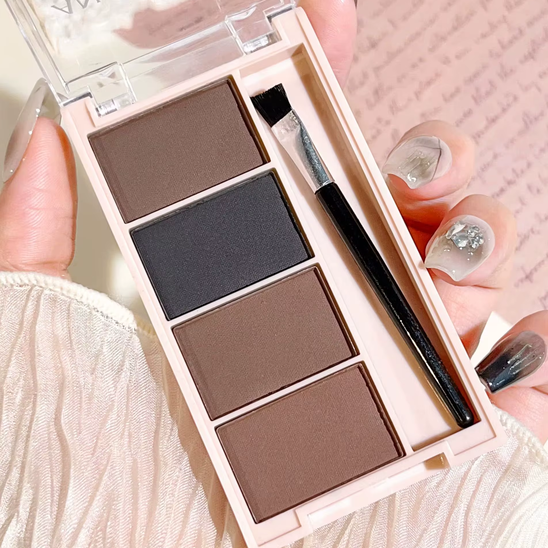 Un ensemble de plateaux de poudre à sourcils de 4 couleurs avec des pinceaux en tons gris et marron mat pour un rendu